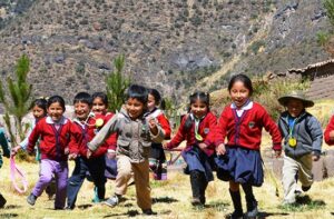 Glada barn iklädda skoluniformer springer mot kameran i Peru. 