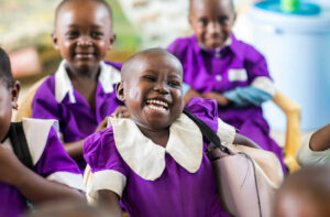 Glada barn från Tanzania i lila kläder ler och skrattar.
