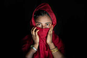 Flicka i Bangladesh som täcker för sin mun med en röd sjal.