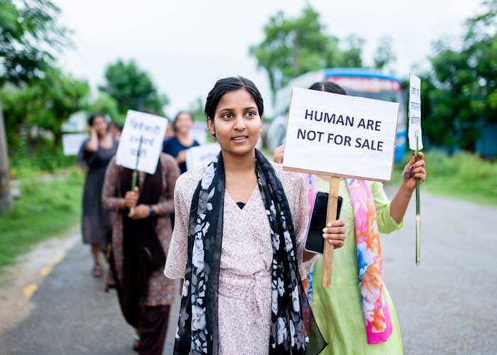 Flicka i Nepal med en skylt med texten Humans are not for sale