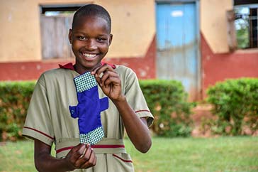 Femtonåriga Zarinah från Uganda håller upp ett mensskydd som hon sytt själv.