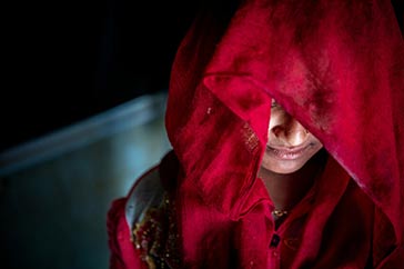 Flicka i Bangladesh som döljer större delen av sitt ansikte med en röd sjal.