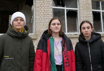 Amina 14 år och två kompisar framför deras skola framför deras skola som skadats i striderna.