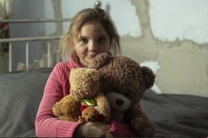 Ukrainsk flicka med nalle i famnen