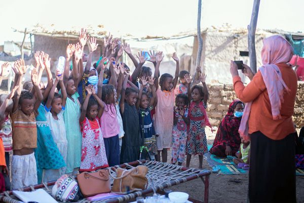 Nahid Ali från Plan International tar kort på en grupp barn i ett flyktingläger i Sudan.
