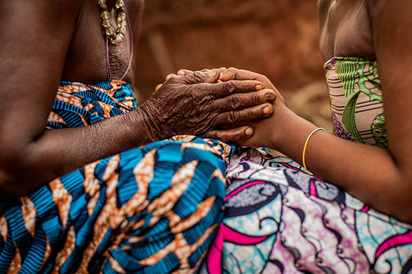 Mormor och dotterdotter håller hand i Benin.